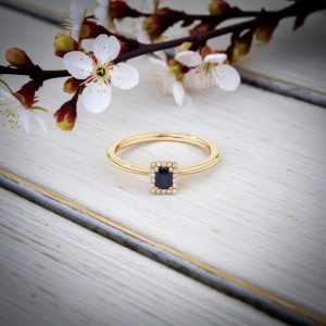 dikdortgen safir merkez tasli ve pirlanta detayli vintage yuzuk dekorlu zemin uzerinde