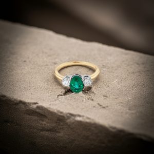 oval kesim zumrut merkez tasli ve yuvarlak pirlanta yan tasli vintage yuzuk dekorlu zemin uzerinde