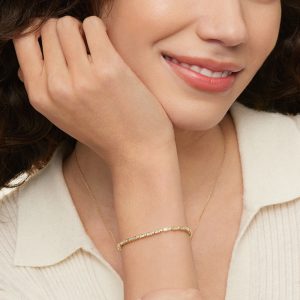 kadın bileğinde sarı altın baget ve yuvarlak taşlı pırlanta suyolu bileklik