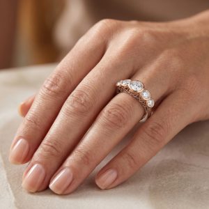 parmakta duran 2.50 karat bezel beştaş pırlanta yüzük, rose altın çerçeve detayları ve beyaz altın halka formuyla şık görünüm