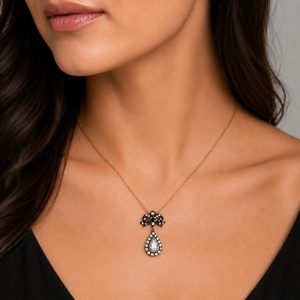 vintage fiyonk motifli damla elmas kolye boyunda görünümde taşlı üst motif ve damla formlu sallantı detayıyla gösteriliyor